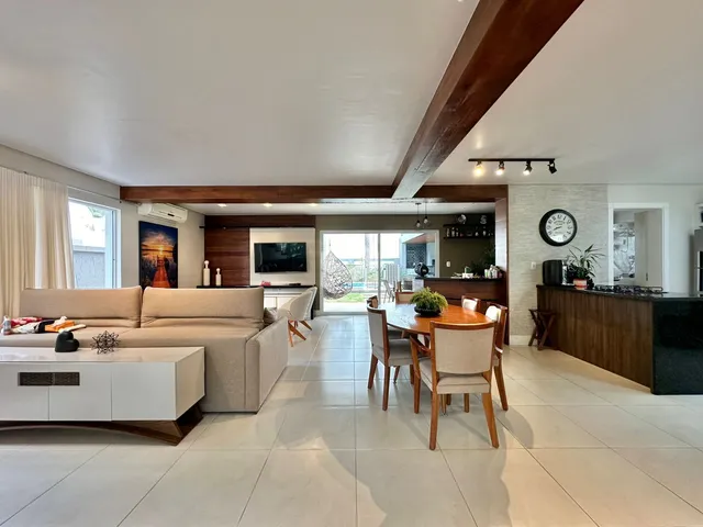 Sala de estar e jantar de um imóvel moderno com piso de cerâmica e vigas de madeira.