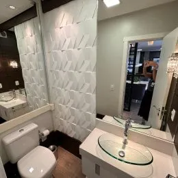 Foto de um banheiro com revestimento branco e louças sanitárias.