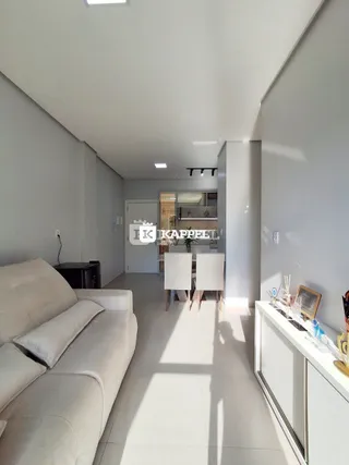 Sala de estar com sofá claro e paredes brancas em um ambiente moderno.