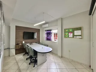 Sala de jantar com mesa longa e parede de madeira em um apartamento.