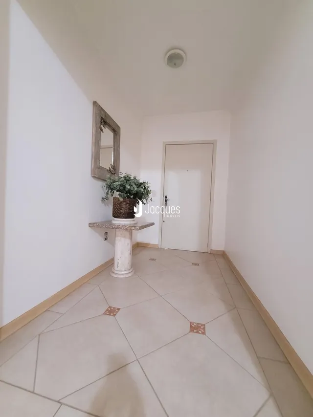 Hall de entrada com piso de cerâmica claro e parede branca.