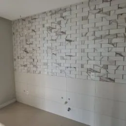Parede revestida com azulejos brancos e rejunte escuro em um ambiente interno.