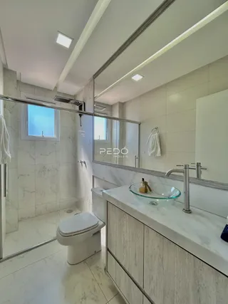 Banheiro moderno com revestimento em mármore e piso claro.