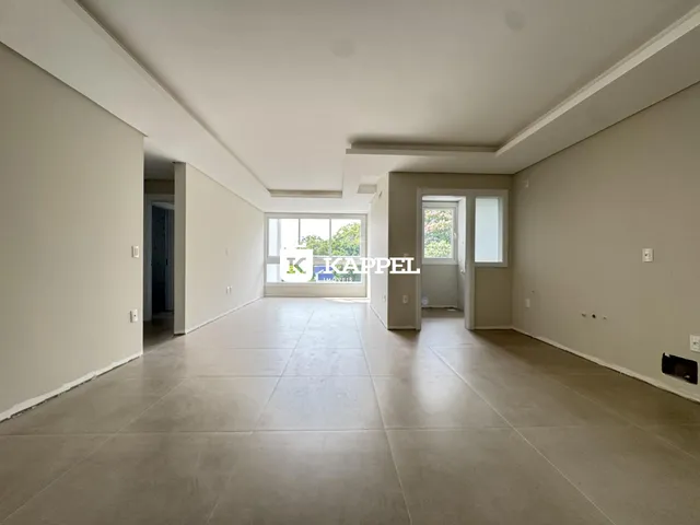 Sala de estar ampla com piso claro e grande janela.