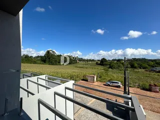 Vista da fachada de uma propriedade com vista para campos abertos.