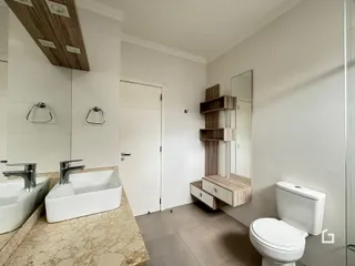Banheiro com bancada de mármore e revestimento branco.