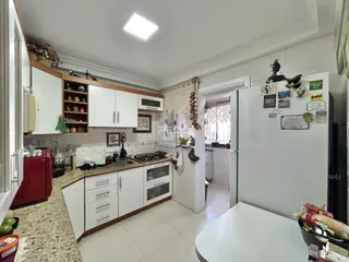 Foto de uma cozinha aberta com armários brancos e piso cerâmico.