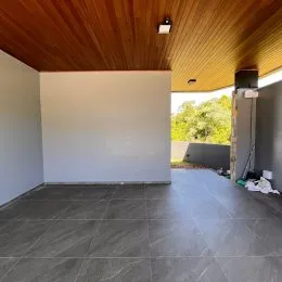 Imagem de um ambiente interno com piso escuro e teto de madeira.