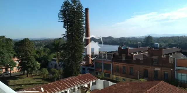 Vista externa de uma propriedade com árvores e água ao fundo.