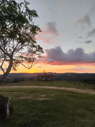 Vista panorâmica de uma paisagem rural com colinas ao pôr do sol.