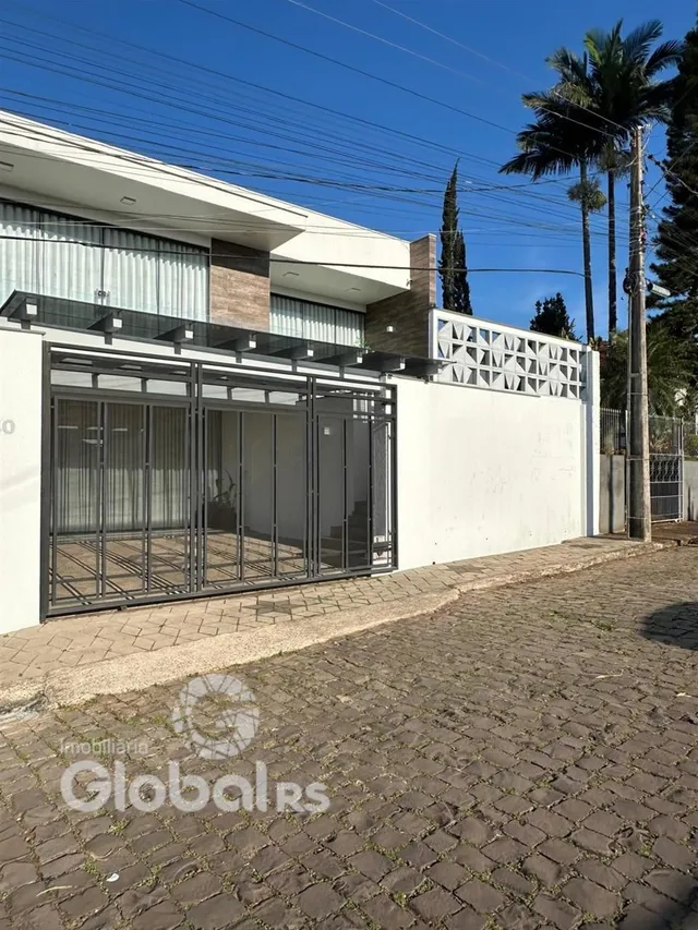 Fachada externa de uma residência em Lajeado, Brasil, com muro branco e portão de metal.