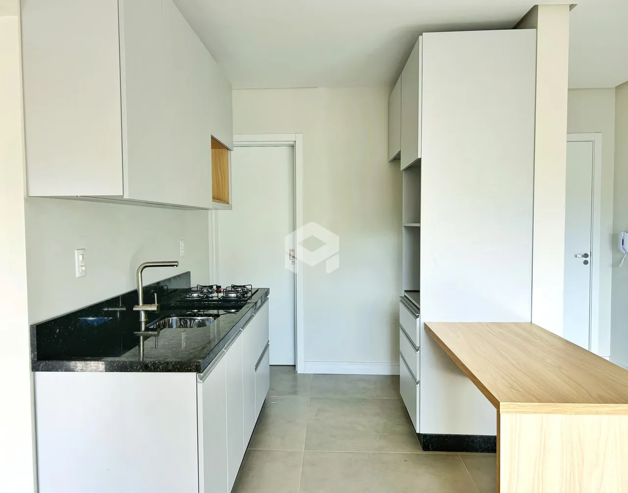 Vista da cozinha moderna com armários brancos e bancada escura.