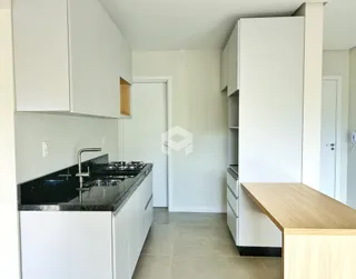 Vista da cozinha moderna com armários brancos e bancada escura.