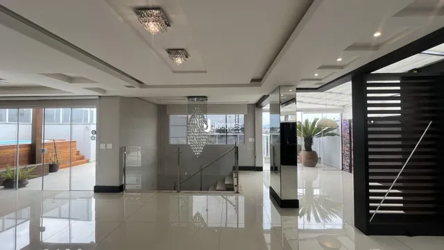 Interior de uma área comum moderna com piso reflexivo e grandes portas de vidro.