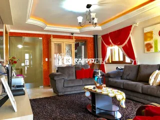Sala de estar com sofás cinzas e cortinas vermelhas em um apartamento.