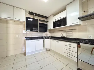 Cozinha moderna com armários brancos e piso de cerâmica clara.