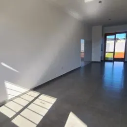 Foto de um ambiente interno amplo com piso escuro e iluminação natural.