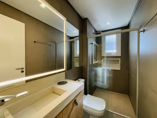 Interior de um banheiro moderno com banheira e box de vidro.