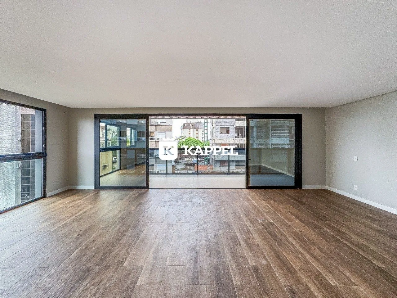 Sala de estar ampla com piso de madeira e portas de vidro.
