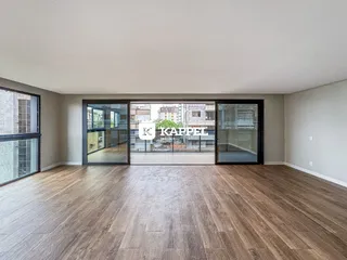 Sala de estar ampla com piso de madeira e portas de vidro.