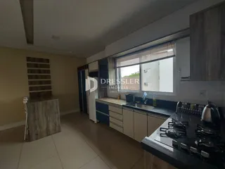 Vista interna de uma cozinha moderna com armários e piso de cerâmica.