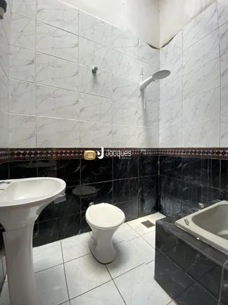 Foto interna de um banheiro com revestimento de azulejos brancos e pretos.