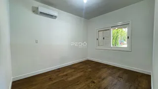 Ambiente interno de uma sala com piso de madeira e janela.