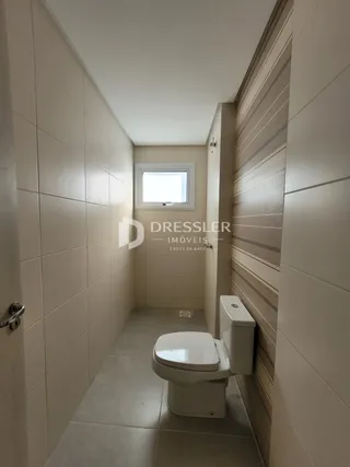 Interior de um corredor com banheiro revestido em cerâmica.