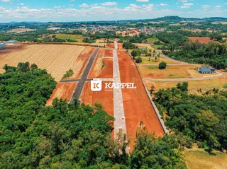 Vista aérea de uma propriedade rural com campos abertos e vegetação densa ao redor.