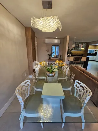 Uma sala de jantar com mesa de vidro e cadeiras brancas.