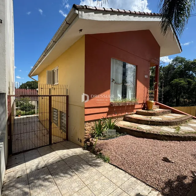 Fachada de uma casa em Lajeado, Brasil, com portão de ferro e área externa pavimentada.