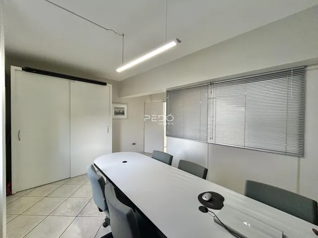 Uma sala de jantar clara com piso de cerâmica e janelas com persianas.