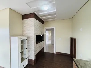 Sala de estar com piso de madeira escura e parede de destaque de pedra.