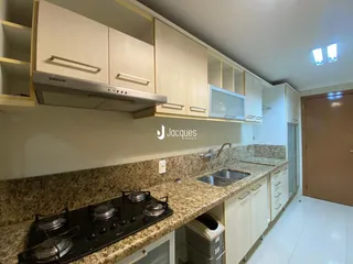 Cozinha com armários claros e bancadas de granito.