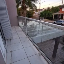 Varanda com piso de cerâmica e guarda-corpo de vidro.