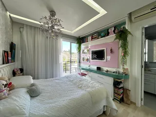 Quarto com decoração clara e vista para o exterior.