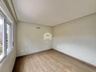 Ambiente interno de uma sala com piso de madeira clara e paredes brancas.