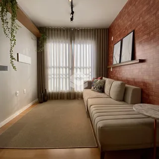 Sala de estar com paredes de tijolo e cortinas claras.