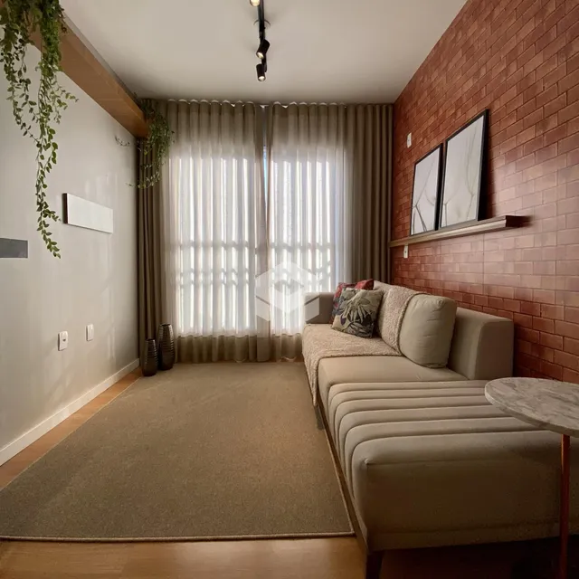 Sala de estar com paredes de tijolo e cortinas claras.