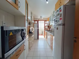 Vista interna de uma cozinha e corredor com piso de cerâmica claro.