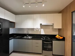 Foto de uma cozinha moderna com armários brancos e bancadas escuras.