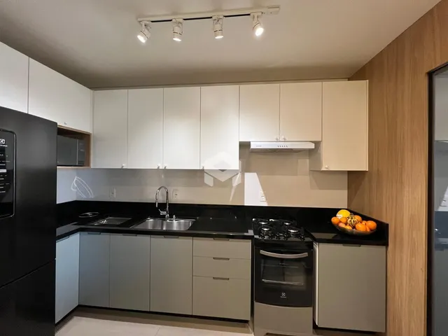 Foto de uma cozinha moderna com armários brancos e bancadas escuras.
