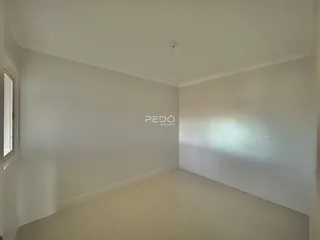 Vista interna de uma sala de estar clara com paredes brancas.