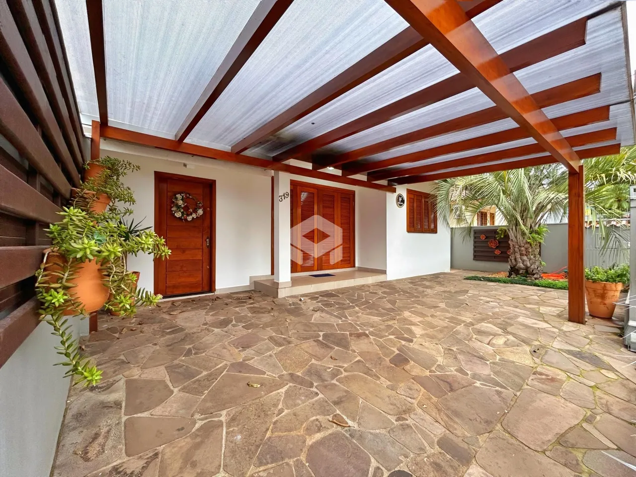Pátio externo com piso de pedra e estrutura de madeira.