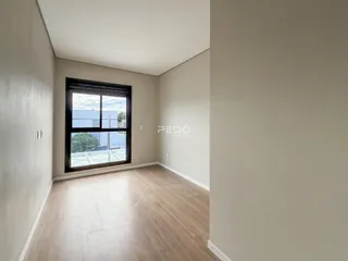 Vista interna de um corredor com piso de madeira clara e parede branca.