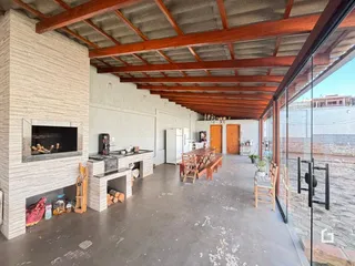 Interior de uma área comum com pé direito alto e vigas de madeira expostas.