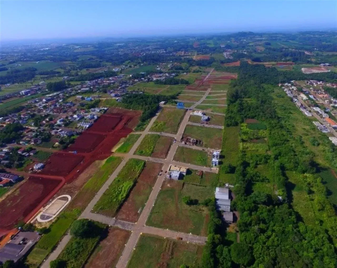 Vista aérea de um loteamento em Lajeado, Brasil, mostrando áreas verdes e campos abertos.