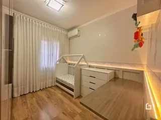 Quarto com piso de madeira clara e cortinas brancas.