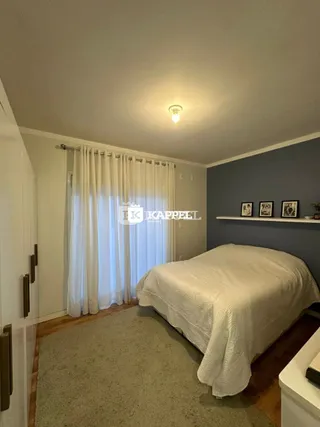 Quarto com cama coberta por lençóis brancos e cortinas.