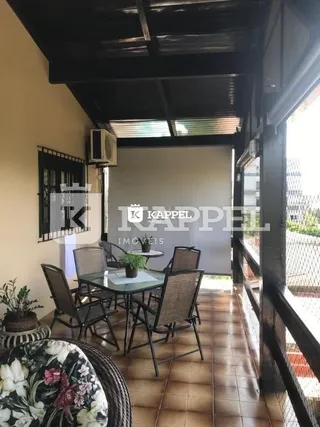 Sala de estar com piso de madeira e estrutura de vigas escura.
